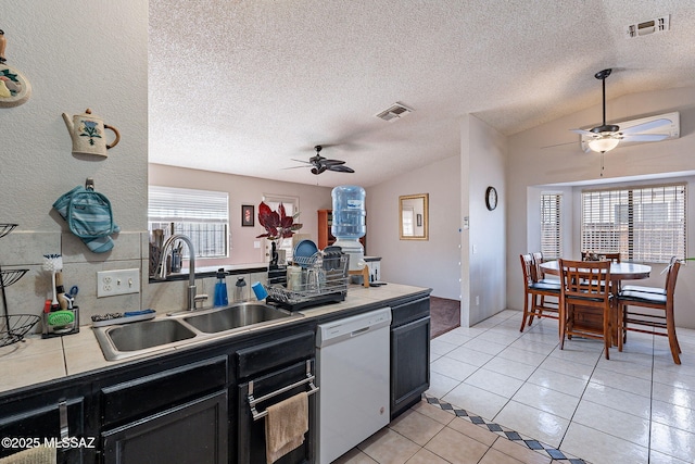 kitchen featuring dishwasher, tile counters, a sink, and visible vents