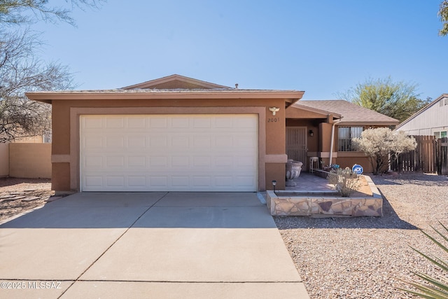 single story home with concrete driveway, fence, and stucco siding