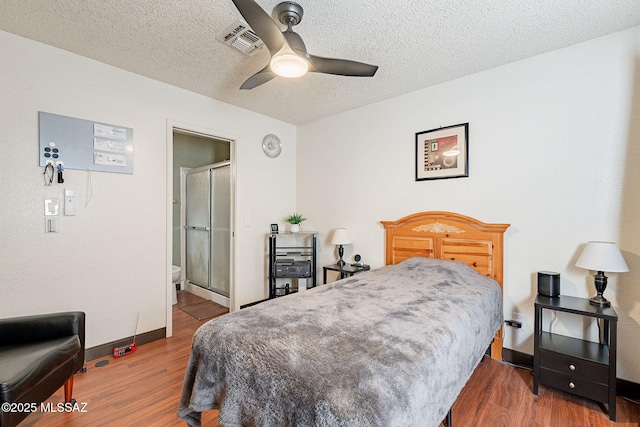 bedroom featuring visible vents, a textured ceiling, baseboards, and wood finished floors