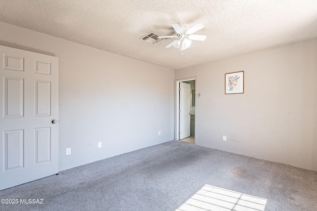 spare room with ceiling fan, visible vents, a textured ceiling, and light colored carpet