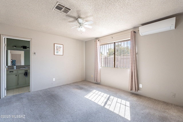 carpeted empty room featuring ceiling fan, a textured ceiling, a wall unit AC, and visible vents