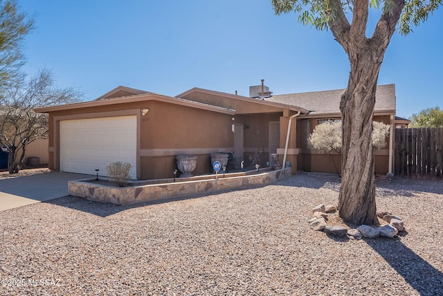 view of front of house with an attached garage, driveway, fence, and stucco siding