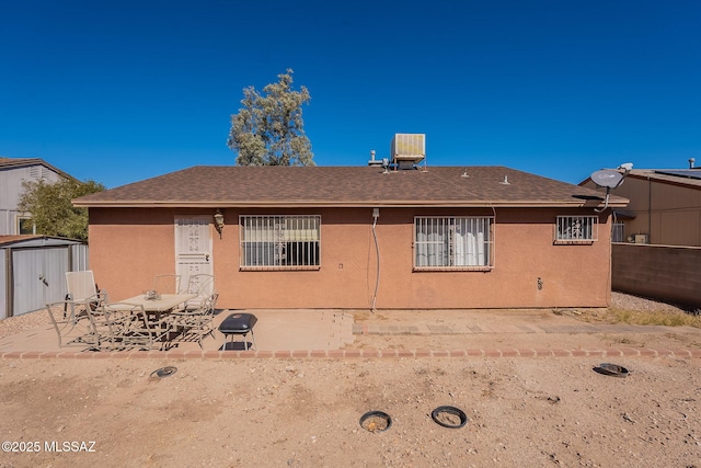 back of house with a storage unit, outdoor dining area, an outdoor structure, a patio area, and stucco siding