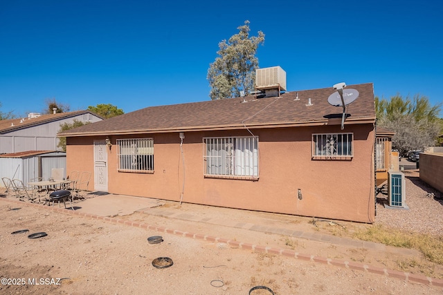 back of property featuring a shingled roof, a patio area, and stucco siding