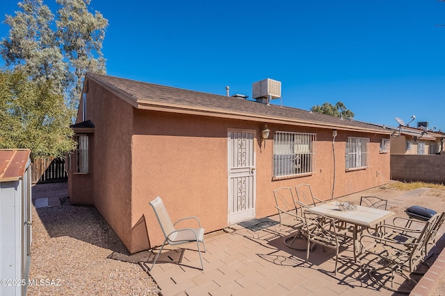 back of property with cooling unit, a patio area, fence, and stucco siding