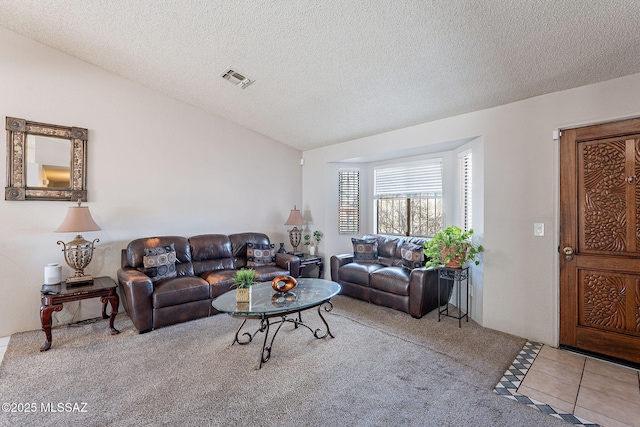 living area with visible vents, vaulted ceiling, a textured ceiling, and tile patterned floors