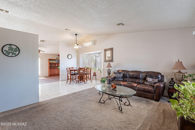 living area with light tile patterned floors, lofted ceiling, visible vents, light carpet, and a wall mounted air conditioner