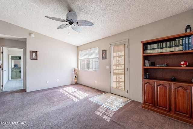 interior space featuring lofted ceiling, ceiling fan, a textured ceiling, and carpet flooring