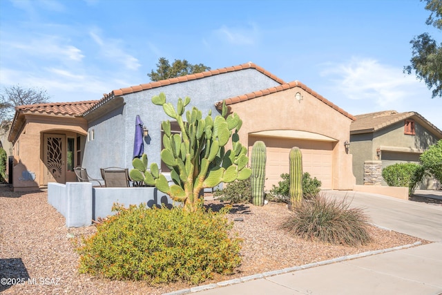 mediterranean / spanish home featuring a tile roof, stucco siding, concrete driveway, and a garage