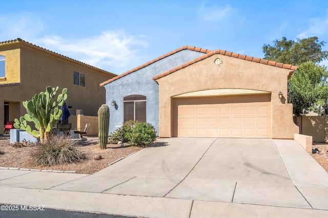 mediterranean / spanish home featuring stucco siding, an attached garage, driveway, and a tiled roof