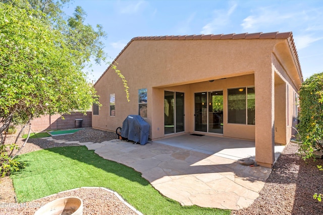 rear view of house featuring stucco siding, fence, a tile roof, and a patio area