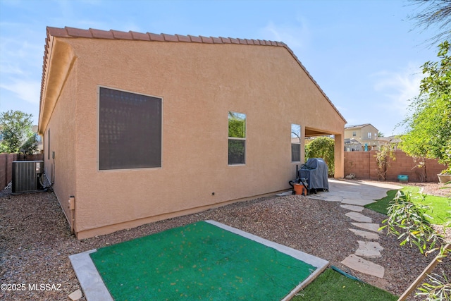 rear view of property featuring stucco siding, a patio, central AC unit, and fence