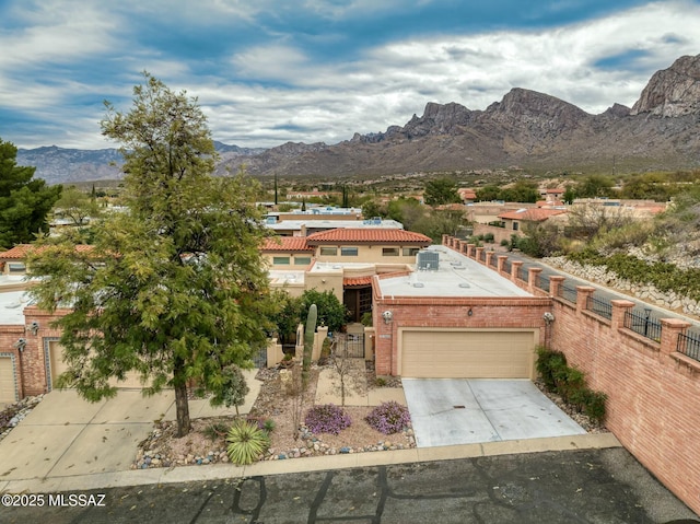 view of front facade featuring fence, a mountain view, concrete driveway, a garage, and brick siding