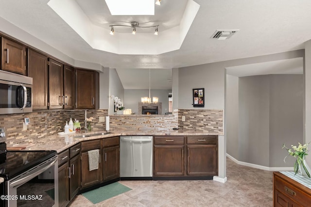 kitchen featuring visible vents, a tray ceiling, a skylight, a sink, and stainless steel appliances