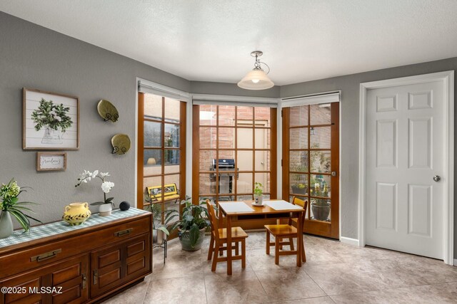 dining room with baseboards, a textured ceiling, and a textured wall