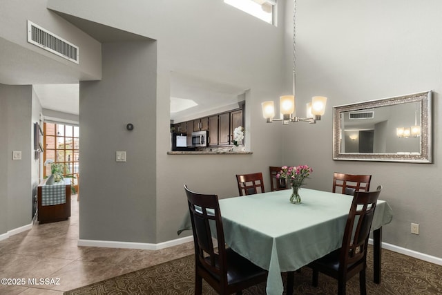 dining area featuring visible vents, an inviting chandelier, a high ceiling, and baseboards