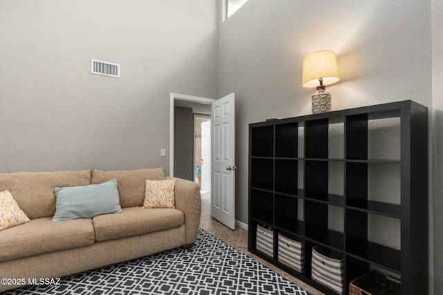 carpeted living room featuring visible vents and a towering ceiling