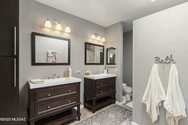 full bathroom featuring toilet, two vanities, and a sink