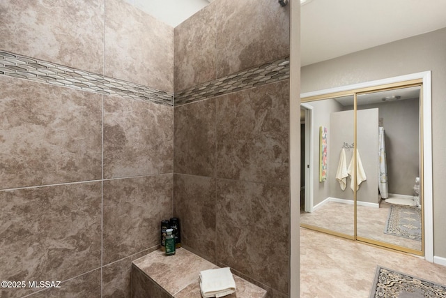 full bath featuring baseboards and a tile shower