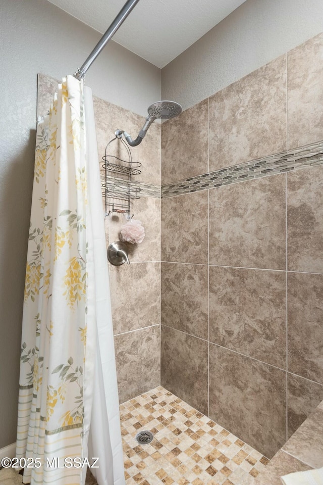 full bathroom featuring tiled shower and a textured wall