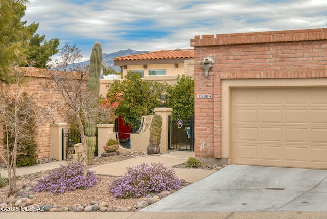 view of front of property with stucco siding, a gate, fence, a mountain view, and a garage