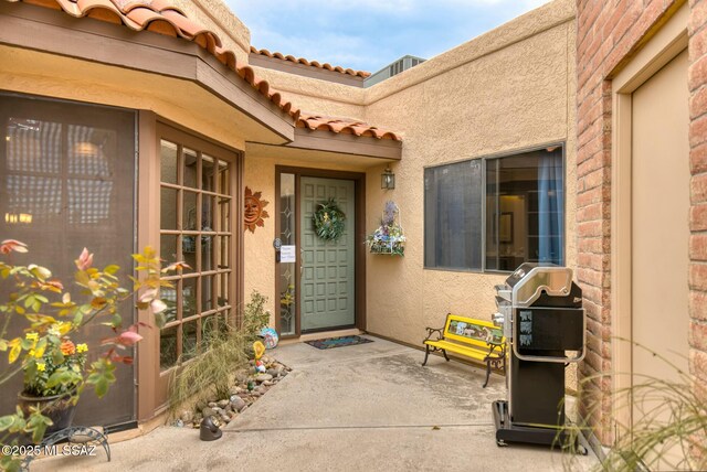 entrance to property with a tiled roof and stucco siding