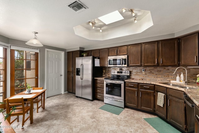 kitchen featuring visible vents, stainless steel appliances, a raised ceiling, and a sink