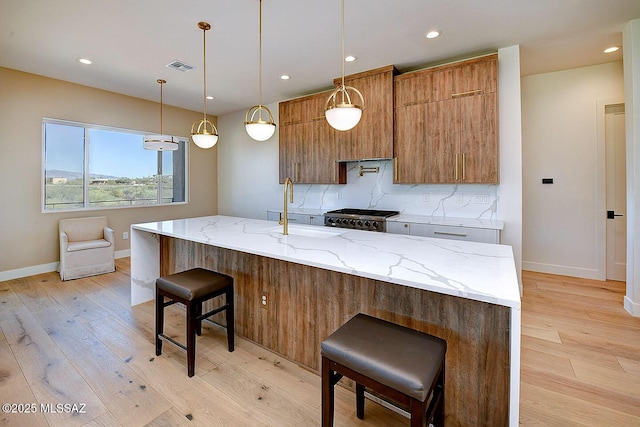 kitchen with visible vents, backsplash, stove, a sink, and modern cabinets