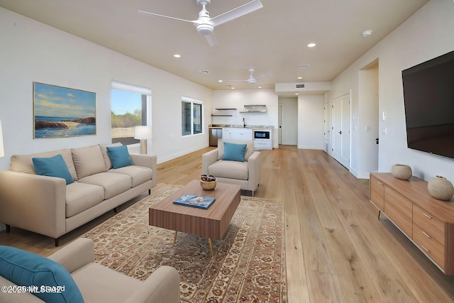 living room featuring baseboards, light wood-type flooring, and recessed lighting