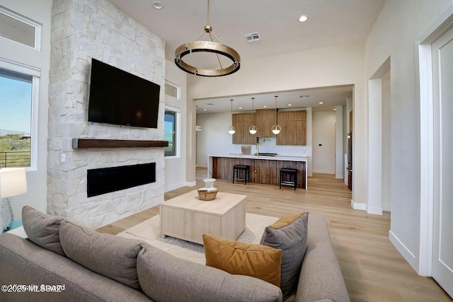 living room with light wood finished floors, a fireplace, visible vents, and baseboards