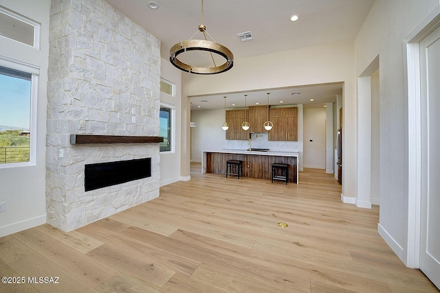 unfurnished living room featuring baseboards, visible vents, a stone fireplace, light wood-type flooring, and recessed lighting