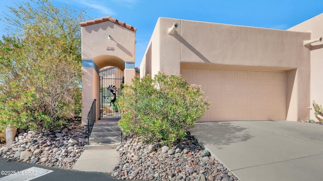 view of front of home featuring stucco siding, concrete driveway, and a gate