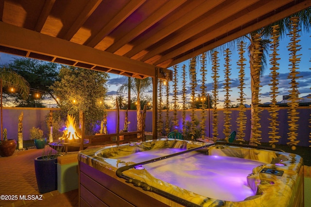 patio terrace at dusk with a fenced backyard and an outdoor hot tub