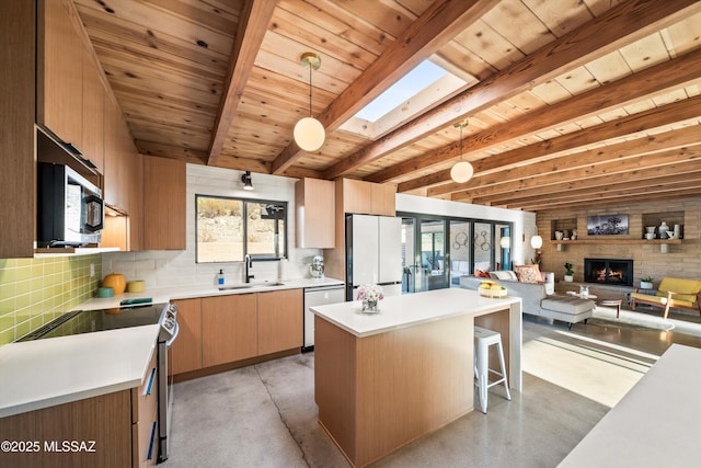 kitchen featuring light countertops, beam ceiling, a skylight, stainless steel appliances, and a sink