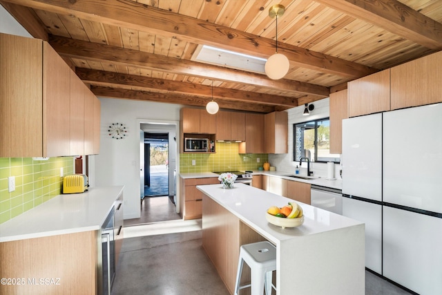 kitchen featuring finished concrete flooring, a sink, stainless steel appliances, light countertops, and tasteful backsplash