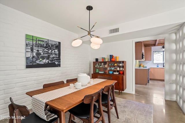 dining space featuring visible vents, brick wall, and concrete floors