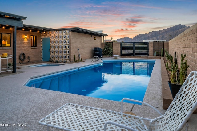 pool at dusk with a mountain view, a fenced in pool, a patio, and a fenced backyard