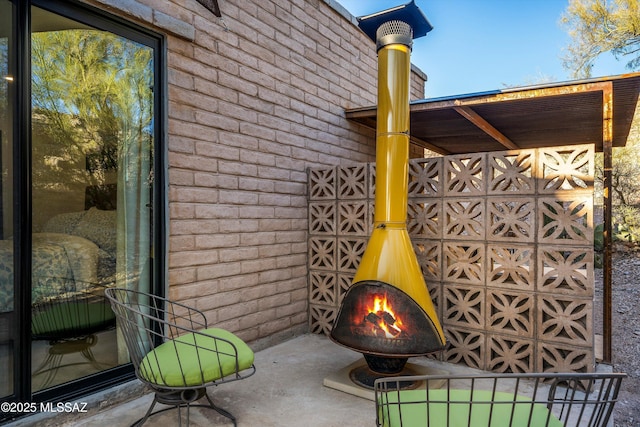 exterior space with brick siding and a warm lit fireplace