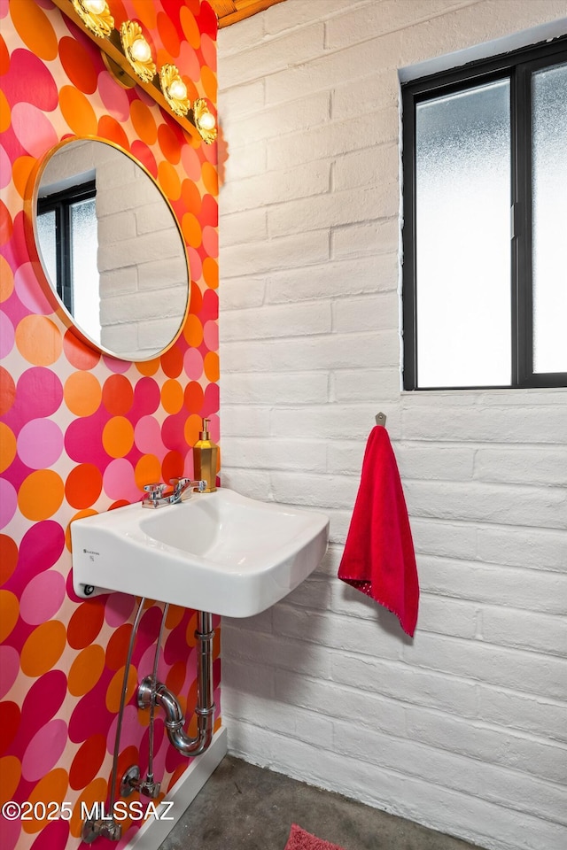 bathroom featuring brick wall and concrete flooring