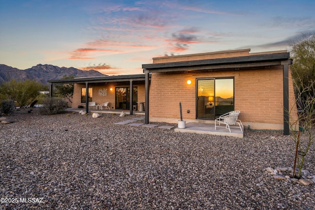 back of property featuring a patio area, a mountain view, and brick siding