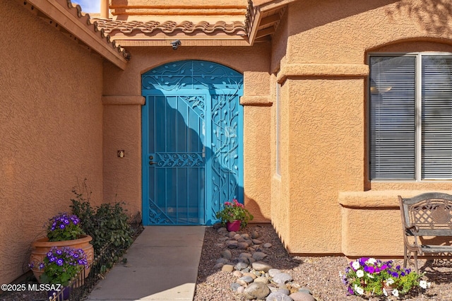 entrance to property with a tile roof and stucco siding