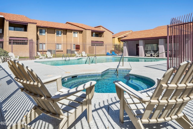 community pool with a patio and fence