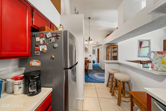 kitchen featuring freestanding refrigerator, light countertops, red cabinets, and light tile patterned floors