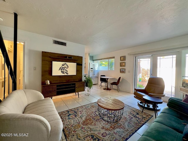 living area with light tile patterned floors, visible vents, and a textured ceiling