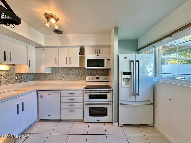 kitchen featuring light tile patterned floors, tasteful backsplash, light countertops, a sink, and white appliances