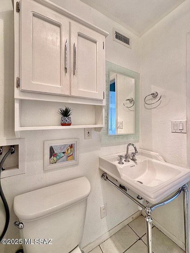 half bath featuring toilet, a sink, tile patterned flooring, and visible vents