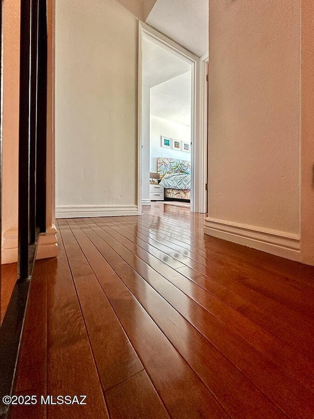 spare room featuring wood-type flooring and baseboards