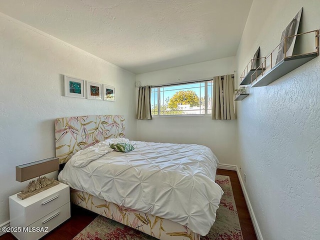 bedroom featuring baseboards, dark wood-type flooring, a textured ceiling, and a textured wall