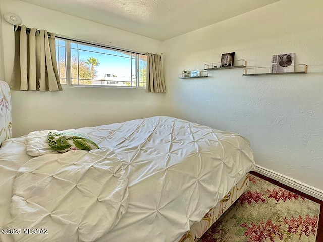 bedroom featuring a textured wall and baseboards