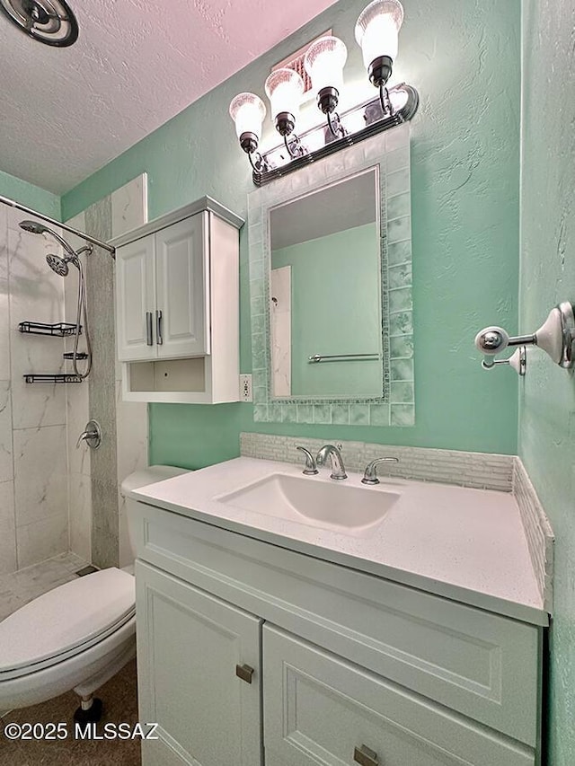 full bath with a textured wall, toilet, a tile shower, a textured ceiling, and vanity